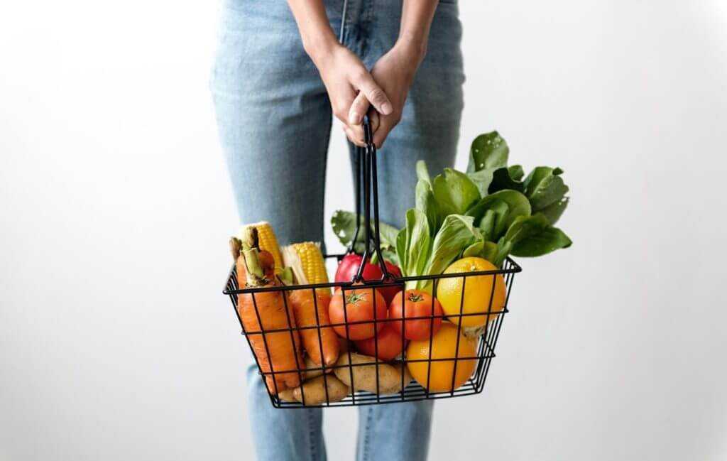 woman holding a basket of fruit and vegetables