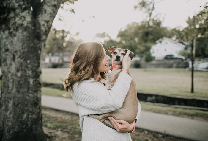 Woman holding small dog and smiling